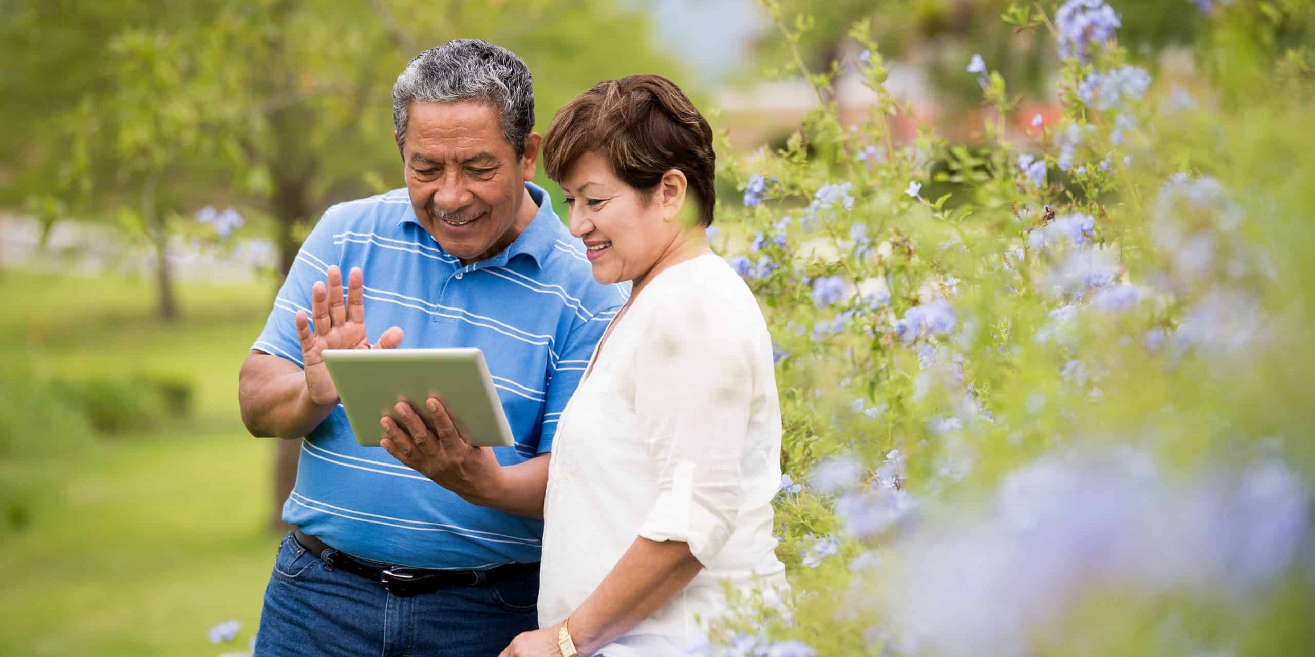 Happy senior couple using digital tablet in a park